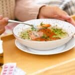 woman-eating-soup-with-medicine-on-tray